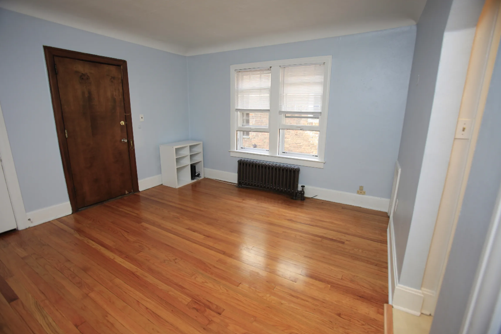 a living room with wooden floors and a window and a wooden door